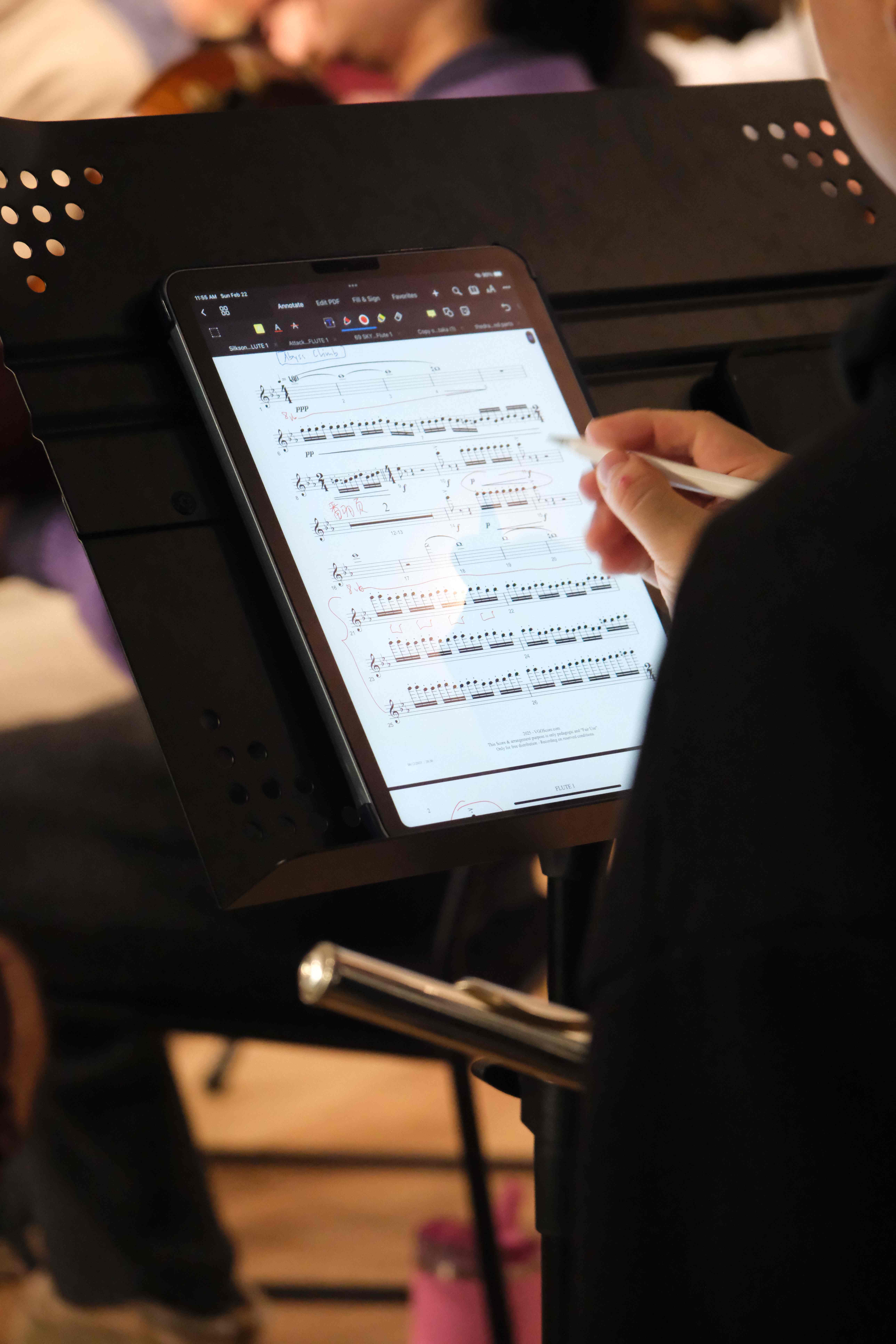 Musician annotating sheet music on a tablet during rehearsal