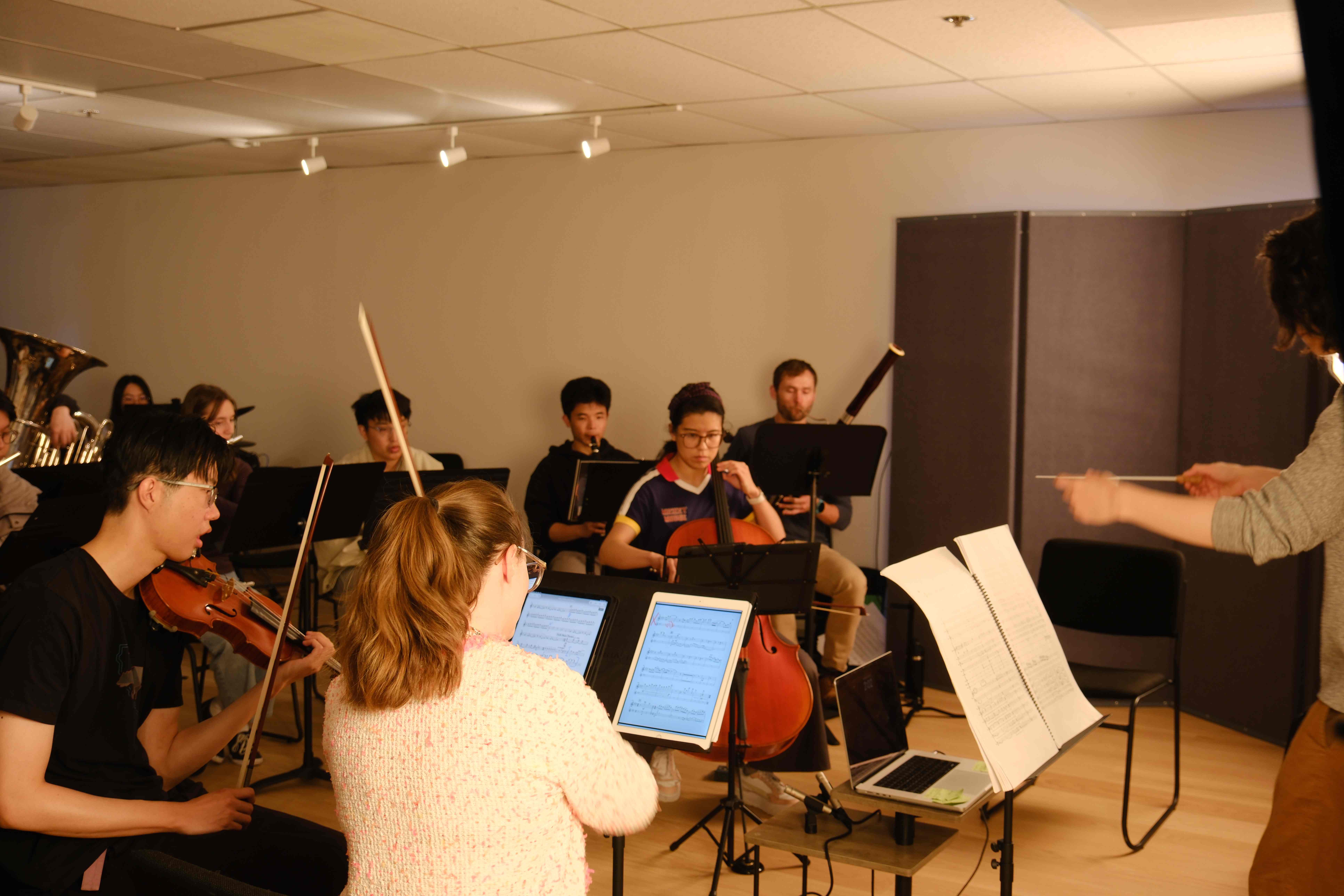 Full orchestra rehearsal in studio with conductor and mixed ensemble