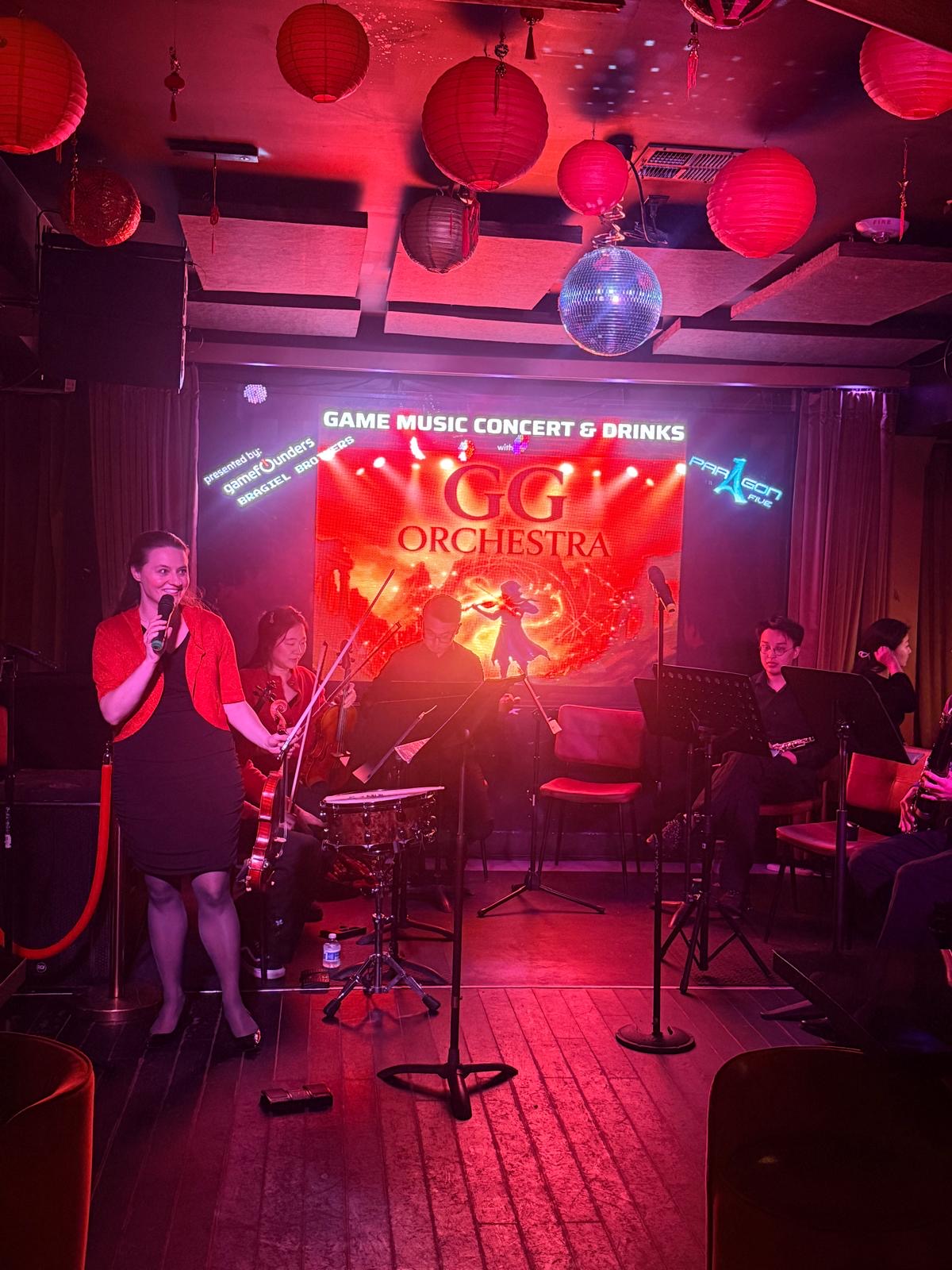 Host introducing GG Orchestra at the GDC private event with red lighting and disco ball