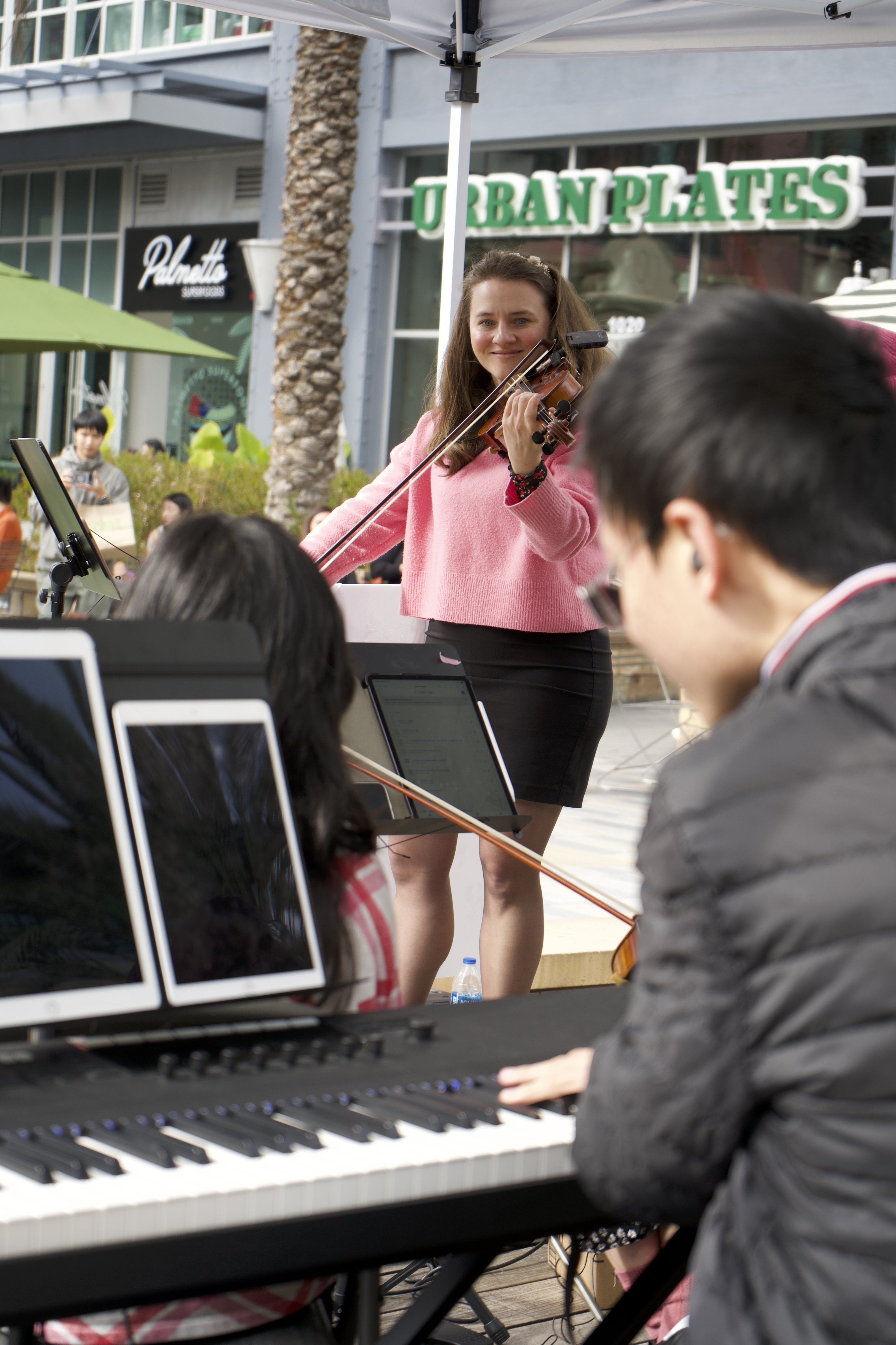 Violinist in pink sweater performing at Santana Row event