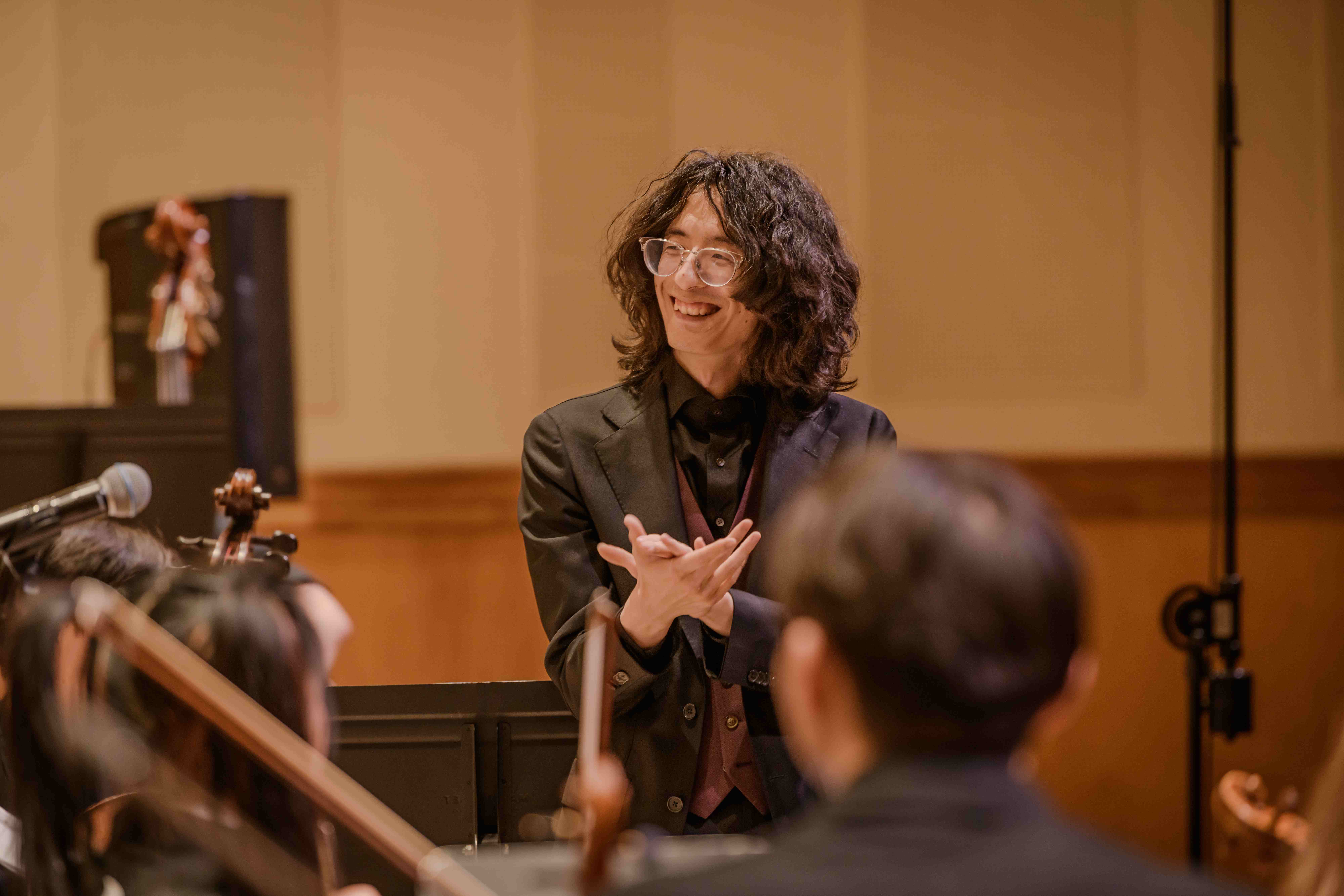 Conductor smiling and applauding the orchestra after a performance
