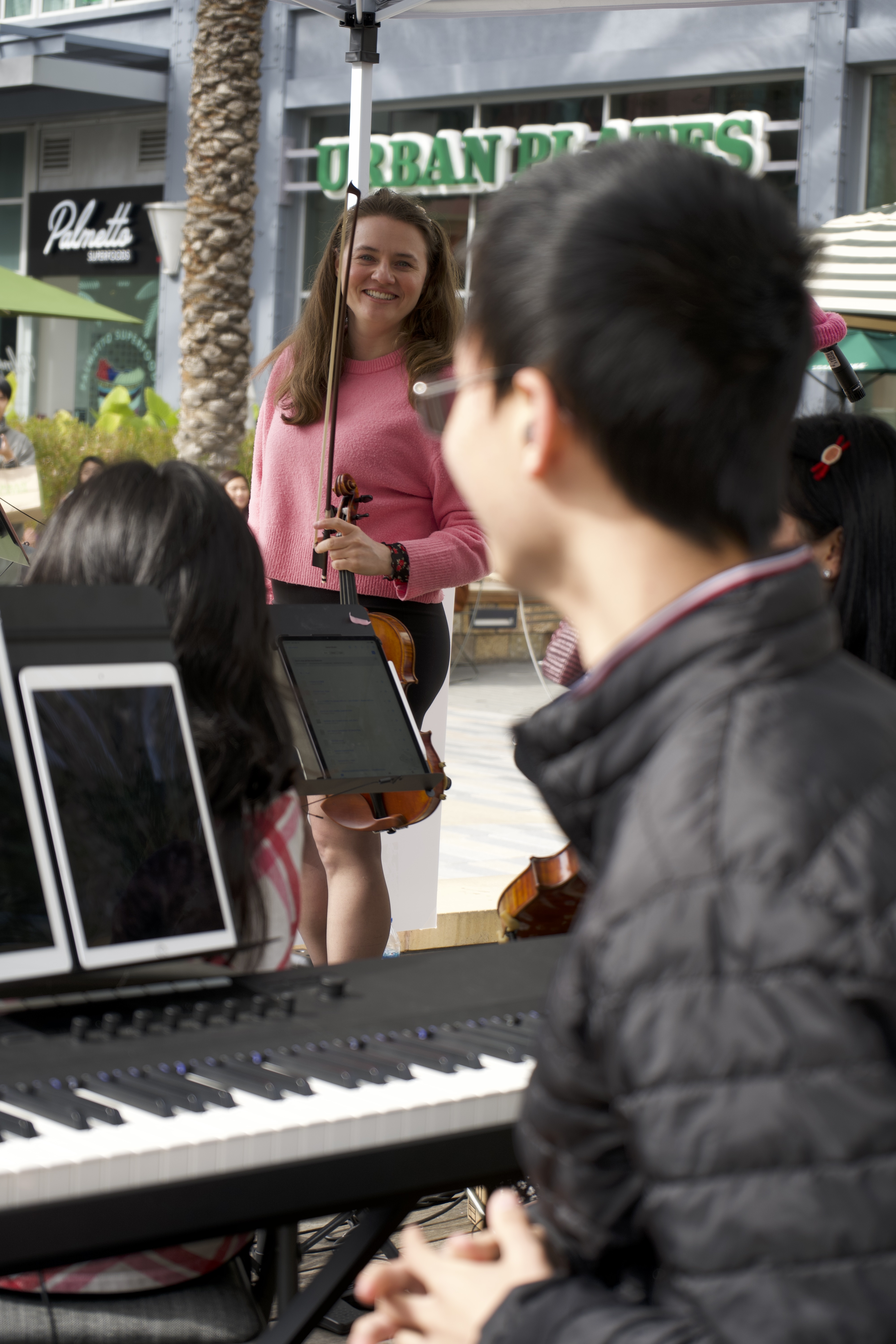 Violinist smiling during outdoor performance at Santana Row